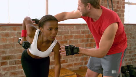 trainer helping client lift weights