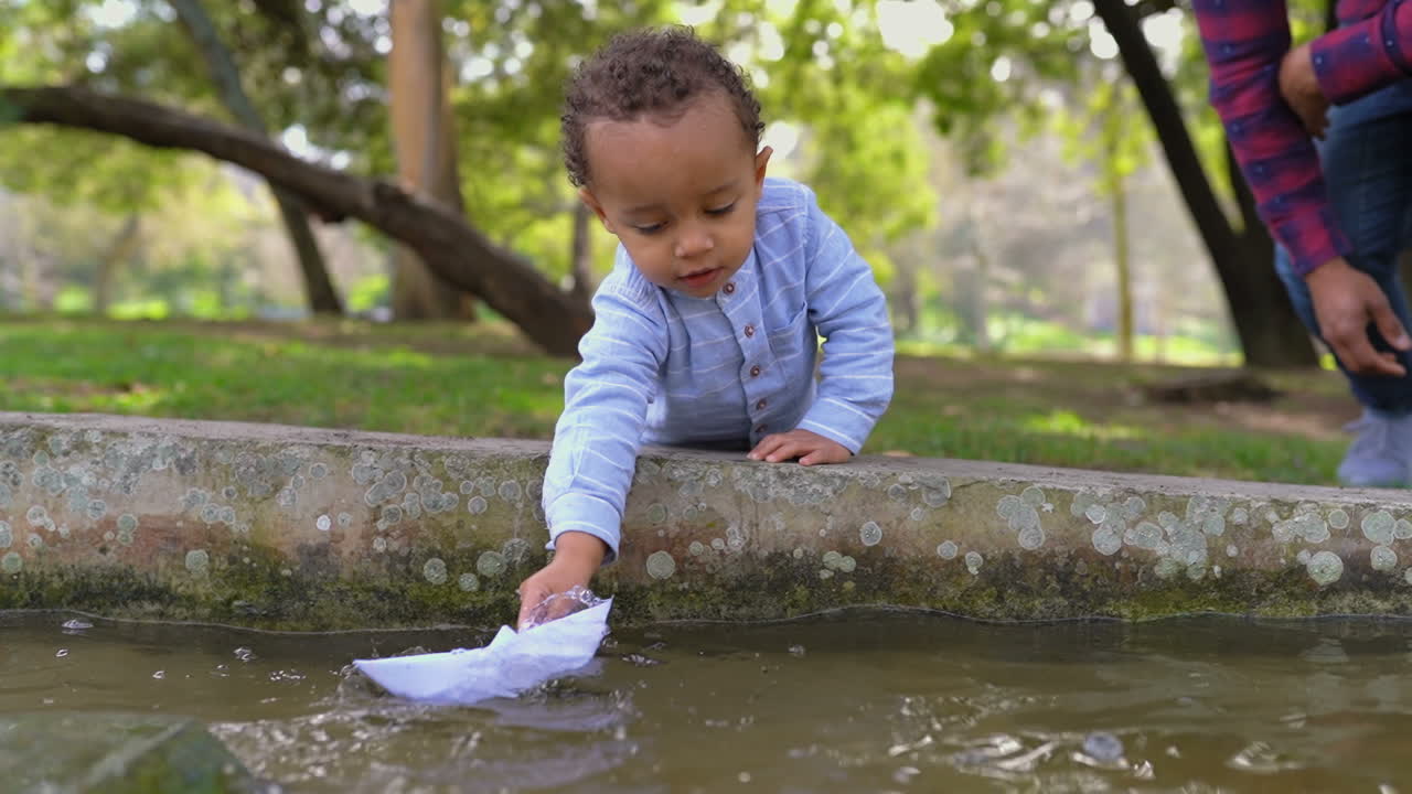 종이 배 를 가지고 놀고 있는 작은 소년 이 항해 하고 침몰 하고 있다