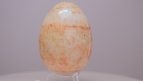 orange and cream marble egg rotating slowly on a turntable in front of a white background