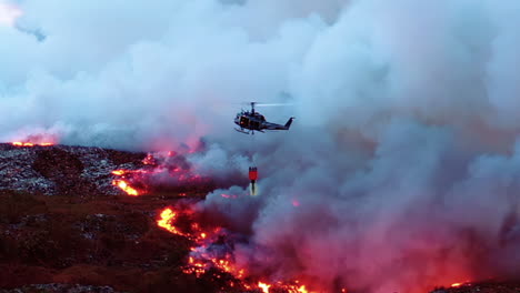 Forest-fire-Helicopter,-Aerial,-drone-shot-following-a-copter,-dropping-water-on-amazon-rainforest-wildfires,-thick-smoke-rising,-dark,-gloomy-evening,-in-Brazil,-South-America