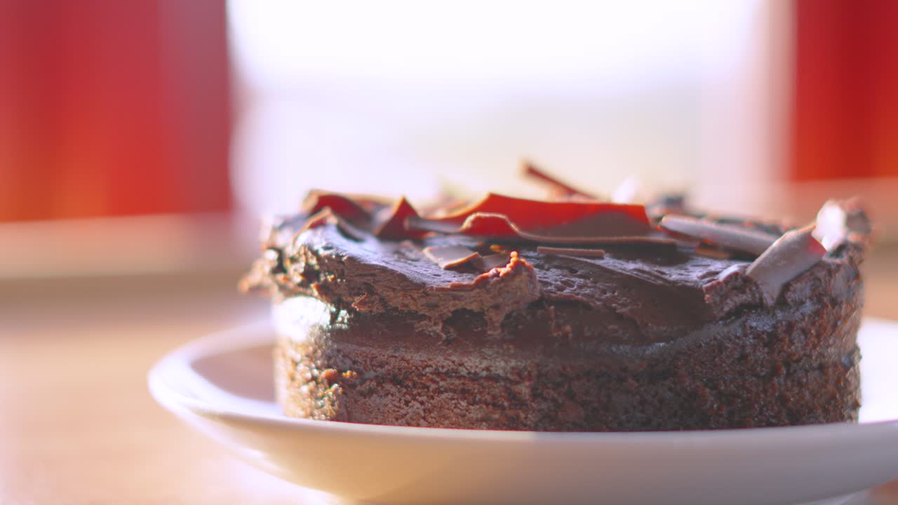 Slow Rotating Shot Around Delicious Chocolate Cake on Plate by Sunlight Window. Indulgent Dessert for Birthday Party or Afternoon Tea Snack. Food Photography.