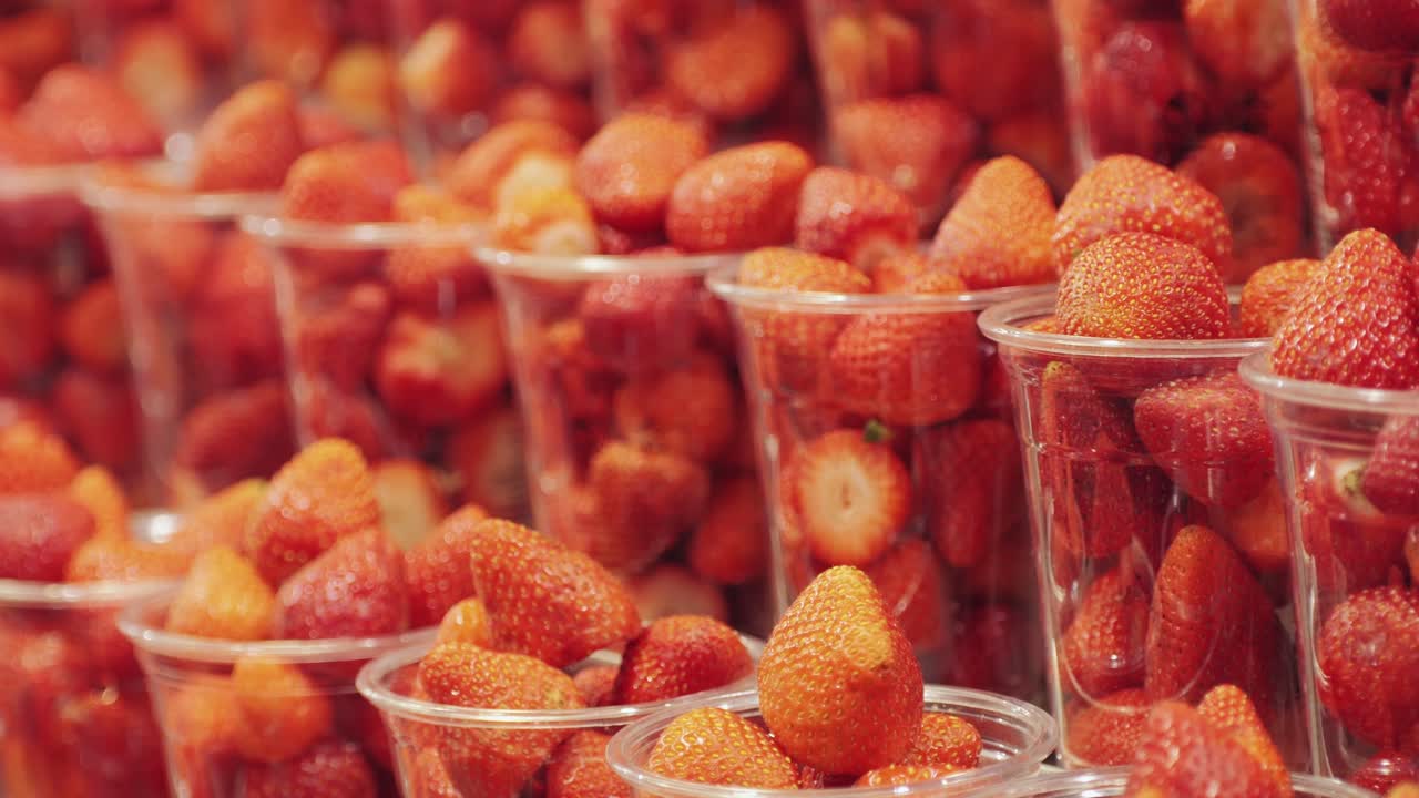 Fresh strawberries in plastic cups on display, showcasing their appetizing, colorful, and delicious qualities