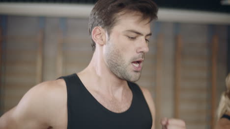 Portrait-of-handsome-man-running-on-treadmill-machine-in-fitness-club.-Closeup