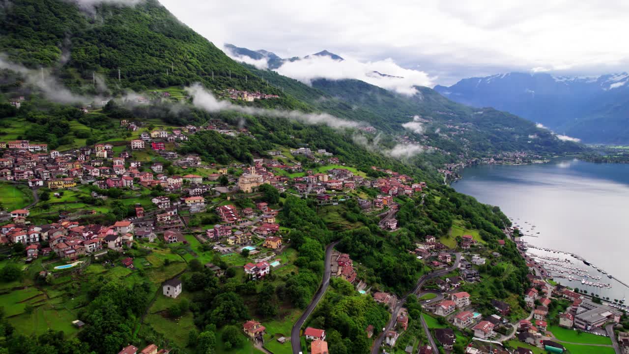 Filmato aereo cinematografico realizzato con drone che sorvola una città storica con tetti rossi, sullo sfondo il Lago di Como e le montagne