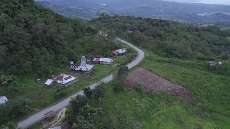motocicleta conduciendo en la carretera con pequeñas casas locales en la isla de sumba indonesia, aérea