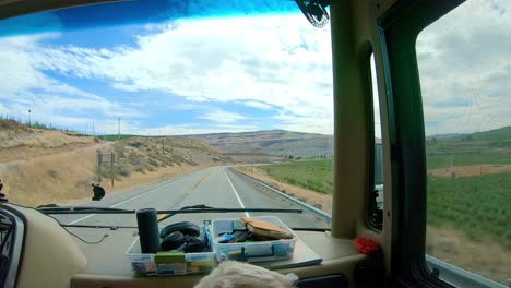 punto de vista del pasajero en un vehículo recreativo de clase grande mientras conduce a través de las tierras altas de okanogan del estado central norte de washington con un perro labradoodle en primer plano