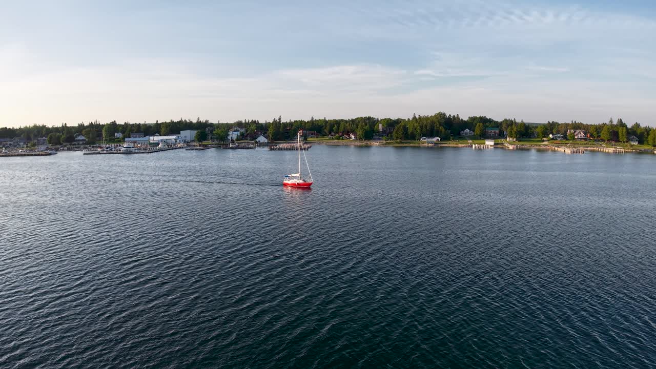 Aerial drone footage of a red buoy floating in calm blue waters near the shoreline of Les Cheneaux Islands in Michigan’s Upper Peninsula