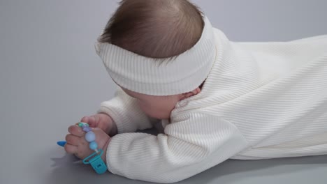 charming baby wearing winter overall is lying on her stomach playing