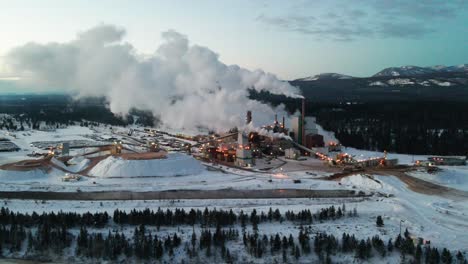 winter sunrise at pulp mill in cranbrook, british columbia: aerial view of industrial facility and specialized machinery processing raw materials for paper production