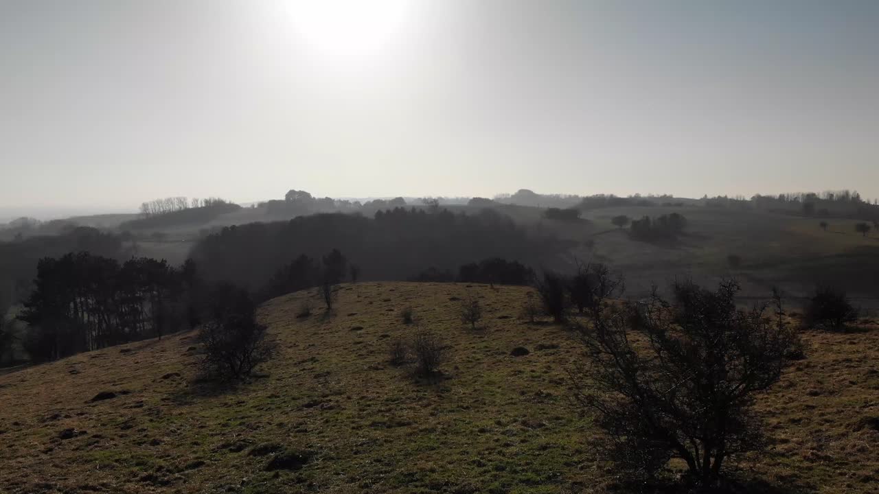 vista aérea de hermosas colinas verdes con árboles y lagos, moviéndose hacia la puesta de sol en odsherred, dinamarca