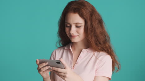 Redheaded-girl-in-front-of-camera-on-turquoise-background.