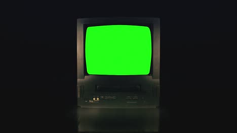 pantalla verde de televisión vintage en una habitación oscura. televisión retro encendiendo con ruido y estática.