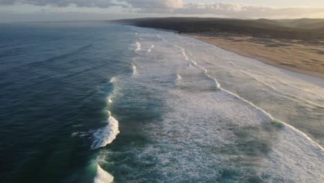 Steady-aerial-view-over-the-sea-waves-splashing-at-the-coastline-during-daytime,-location-recorded-at-Bordeira,-Portugal