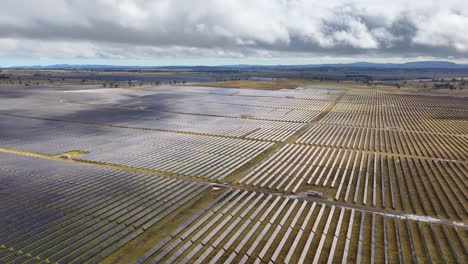 wide drone shot of solar farm panels under cloudy sky, emphasizing renewable energy infrastructure