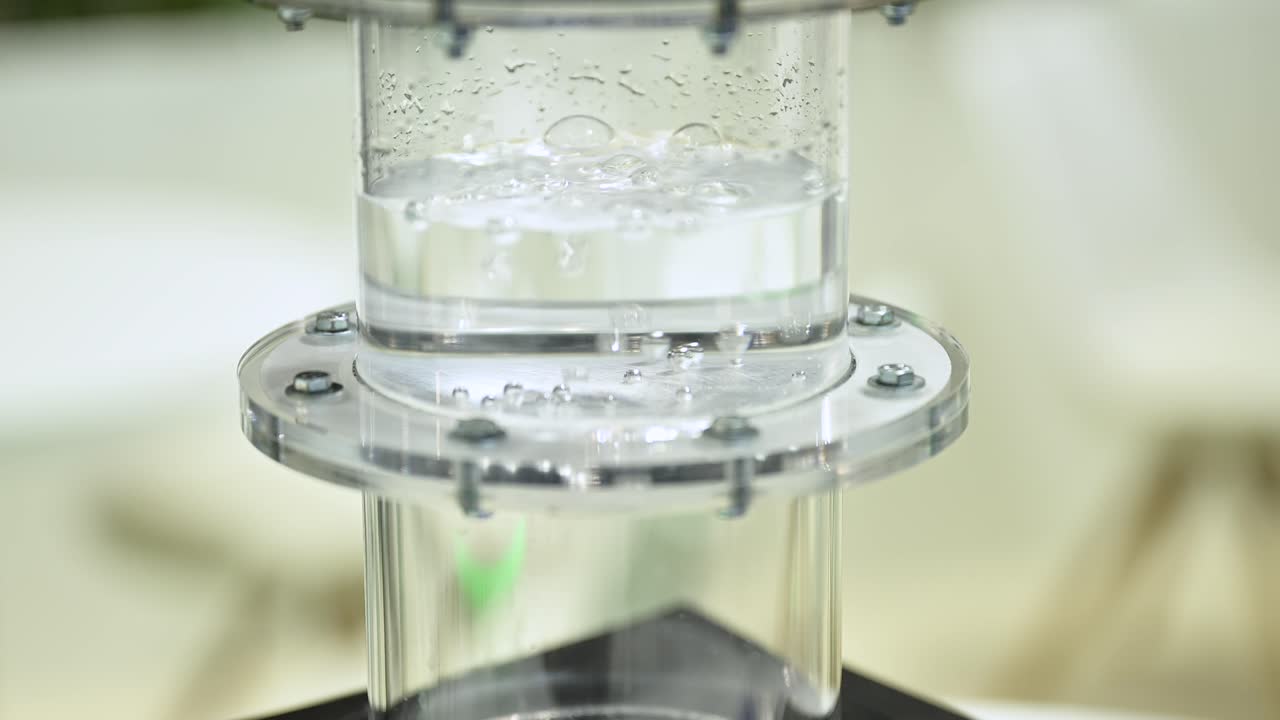 수소 가스는 물로 가득 찬 플라스틱 실린더의 막을 통해 거품을  ⁇ 고 있습니다. 액체에서 작은 거품이 형성되고, 천천히 확대합니다.