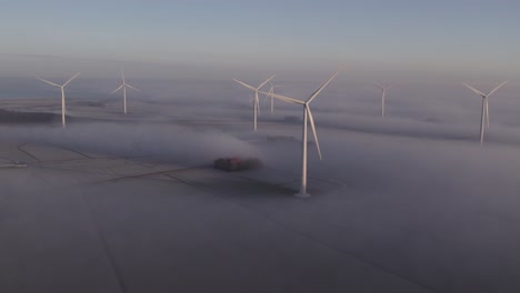 Wind-turbines-spinning-with-low-clouds-at-Cornwerd-during-sunrise,-aerial
