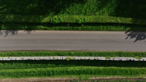 caledon border wall, county tyrone, northern ireland, may 2023. drone top-down view moving right over stone heritage dividing farmlands, country road, green fields and clean aerial symmetry.