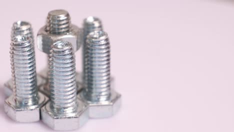 rotating group of galvanized metallic screws close-up. steinless steel bolts isolated on white background.