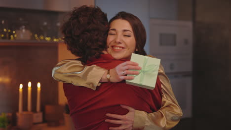 happy woman hugging someone while holding a gift