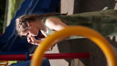 video vertical: niña tocando tambores de plástico en un parque infantil con palos