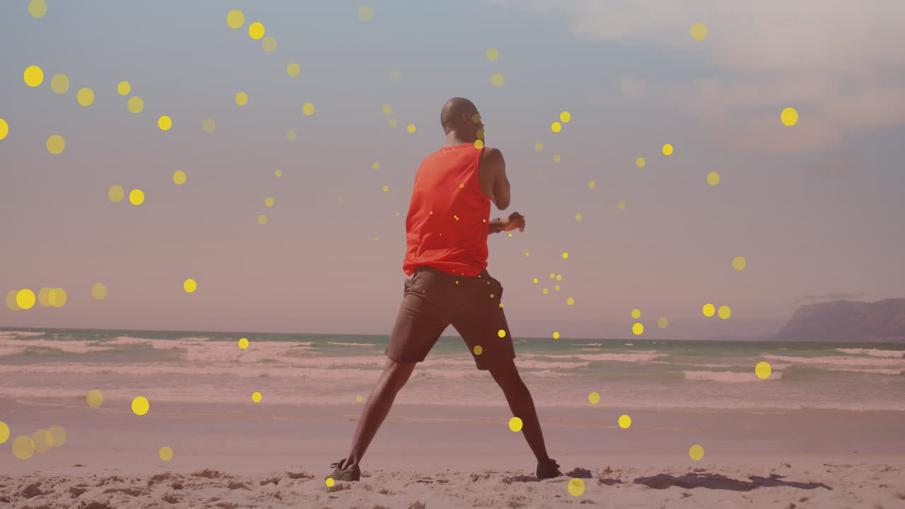 manchas amarillas flotando contra afroamericano hombre en forma realizando ejercicio de estiramiento en la playa