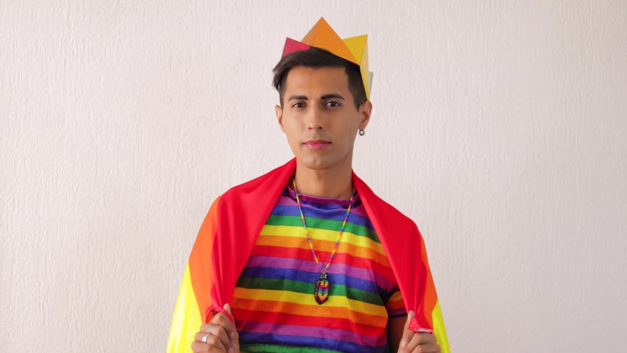 joven gay latino con traje de arco iris y bandera para el desfile del orgullo lgbtq