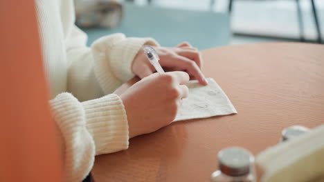 close up of hands sketching creative doodles on napkin using pen at bright cafe table, soft lighting enhances cozy atmosphere, casual scene suggests spontaneous artistic moment