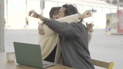 two men celebrating success while working on a laptop outdoors