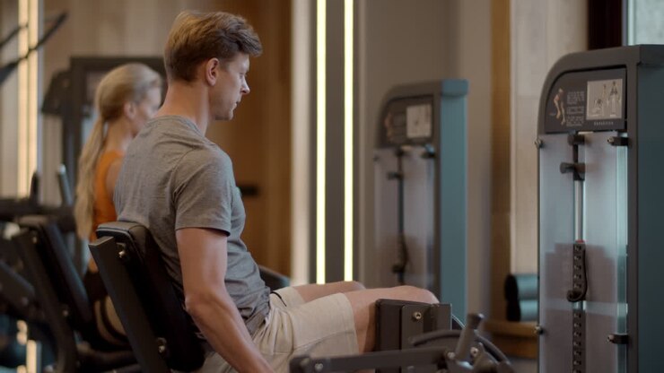 un serio bodybuilder che si allena in palestra. un uomo in forma che fa leg press nello sport club.