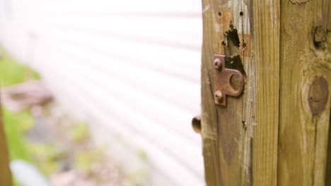 man unlatching old sliding lock and opening gate