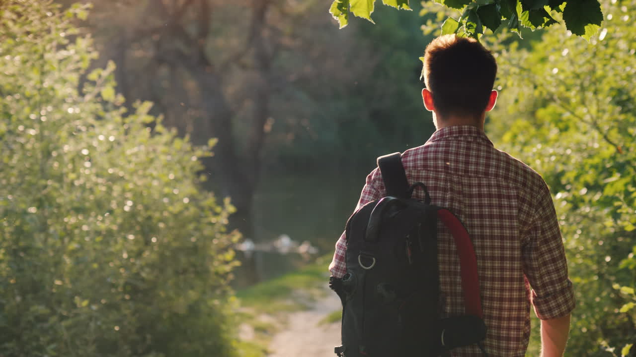 배낭을 메고 있는 10대 소녀가 공원을 산책하며 태양이 카메라에 비치는 아름다운 눈부심