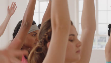 beautiful young mixed race woman exercising in yoga class practicing warrior pose enjoying group physical fitness workout