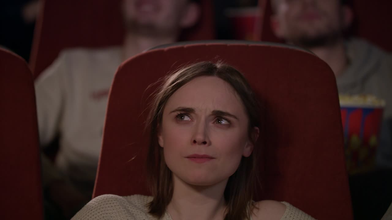 радостные люди смотрят фильм в кинотеатре и едят попкорн