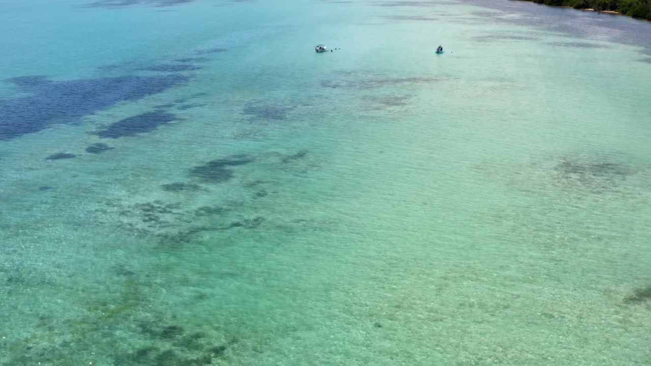 impresionante toma aérea de ojo de pájaro inclinándose en medio de un mar de agua turquesa cristalina que revela pequeños botes turísticos en la hermosa reserva natural de sian ka'an cerca de tulum, méxico