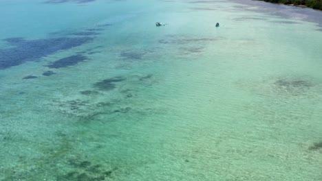 impresionante toma aérea de ojo de pájaro inclinándose en medio de un mar de agua turquesa cristalina que revela pequeños botes turísticos en la hermosa reserva natural de sian ka&#39;an cerca de tulum, méxico