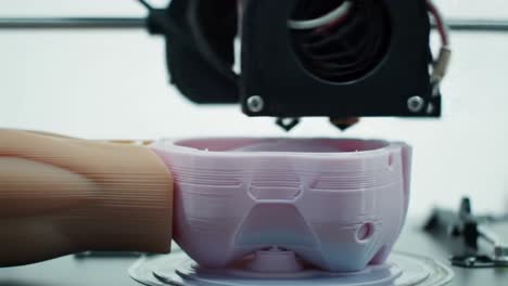 a close-up look at a 3d printer in action, creating intricate details on a prosthetic hand component using advanced fabrication techniques