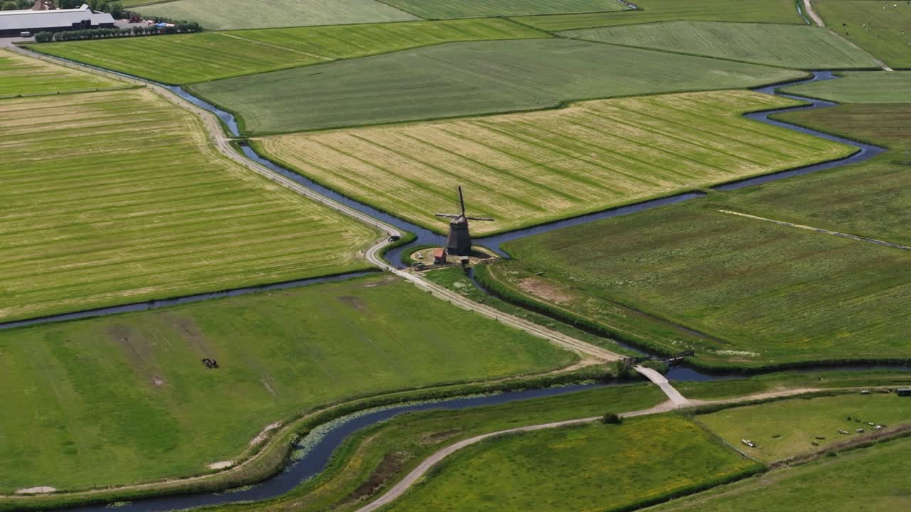 Dutch windmill in green countryside. Vintage cultural heritage building. Aerial drone video.