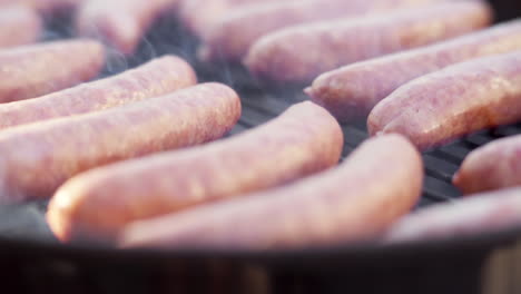 slow motion pull out of sausages grilling on fiery and smokey bbq grill