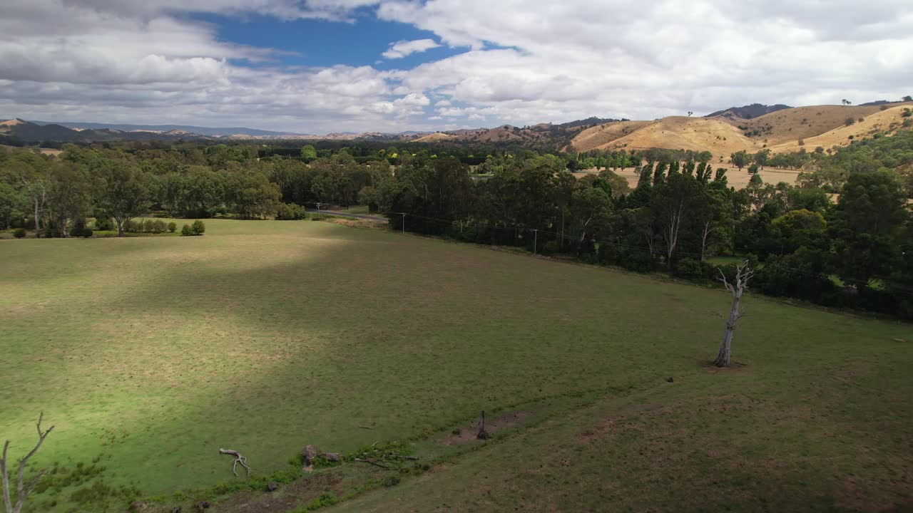 sobre paddocks con el sol rompiendo a través y hacia el río goulburn cerca de eildon, victoria, australia