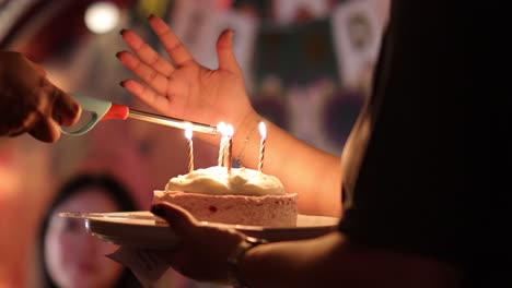 a person lights candles on a birthday cake in a dimly lit restaurant, creating a warm, celebratory atmosphere