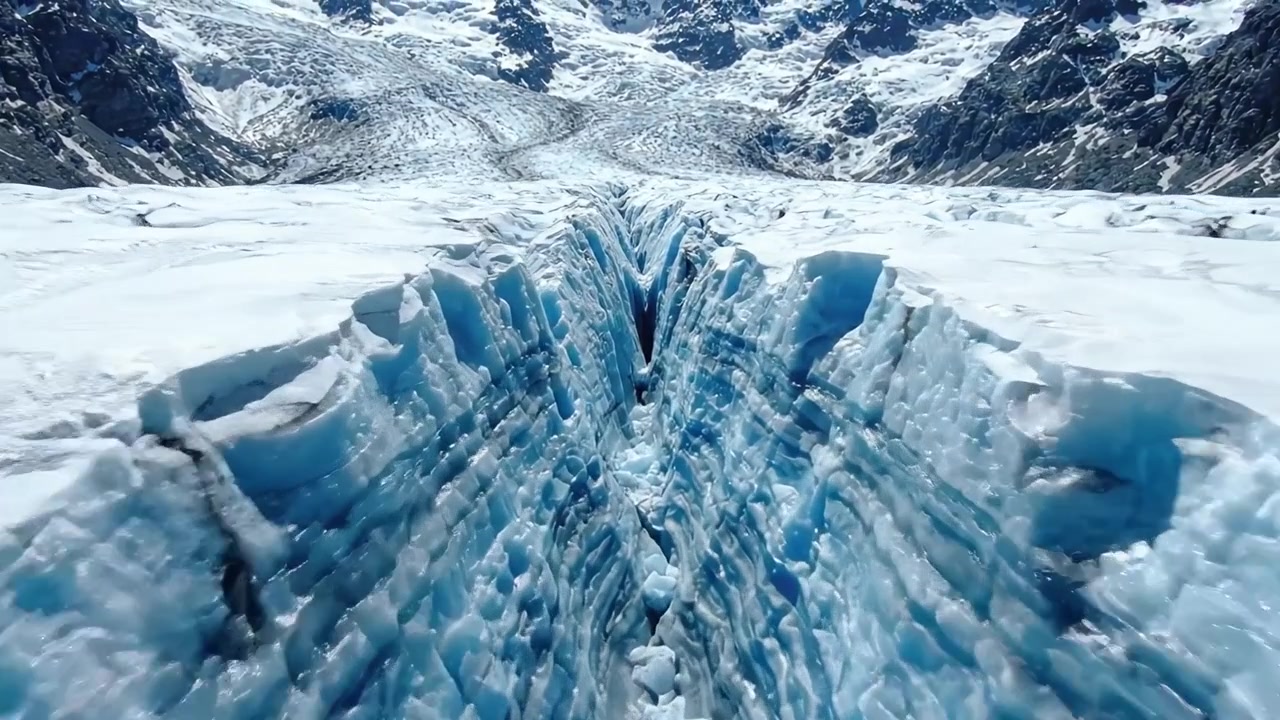 Luftaufnahmen eines majestätischen Gletschers: Atemberaubende Eisformationen und Risse unterstreichen die natürliche Schönheit der gefrorenen Landschaft.