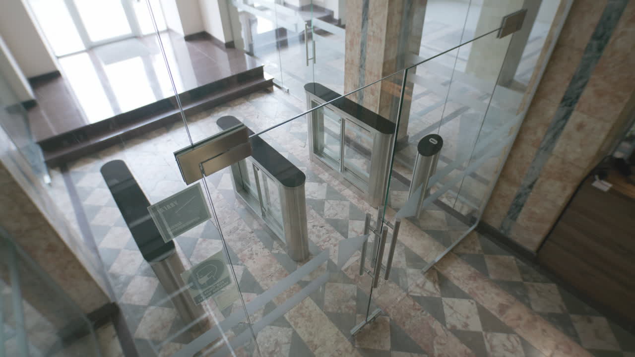 People Entering a Modern Office Building Through Security Turnstiles