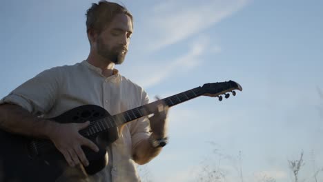 man playing acoustic guitar in a field