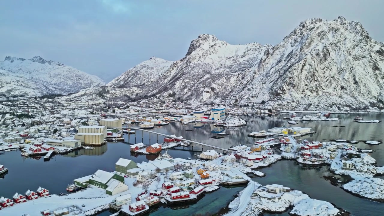 Vila de pescadores coberta de neve com casas coloridas e montanhas escarpadas nas Ilhas Lofoten no inverno.
