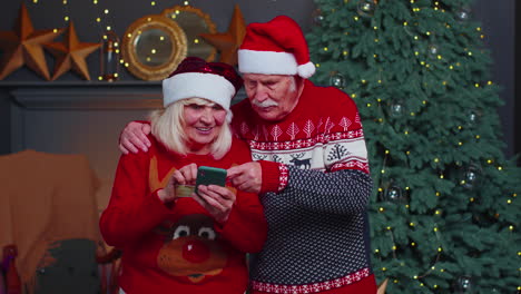 Abuela-De-La-Familia-Mayor-Usando-Tarjeta-Bancaria-De-Crédito-Y-Compras-De-Regalos-De-Navidad-Con-Teléfonos-Inteligentes