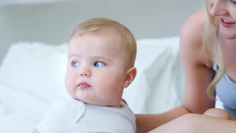 mother lying on bed at home gives baby son kiss