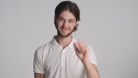 caucasian pleased man in front of camera on gray background.