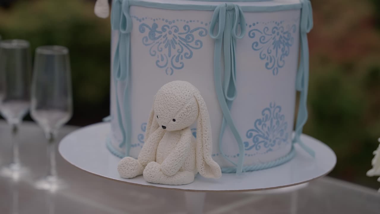 Primer plano de una tarta de baby shower con una figura de conejo blanco de fondant