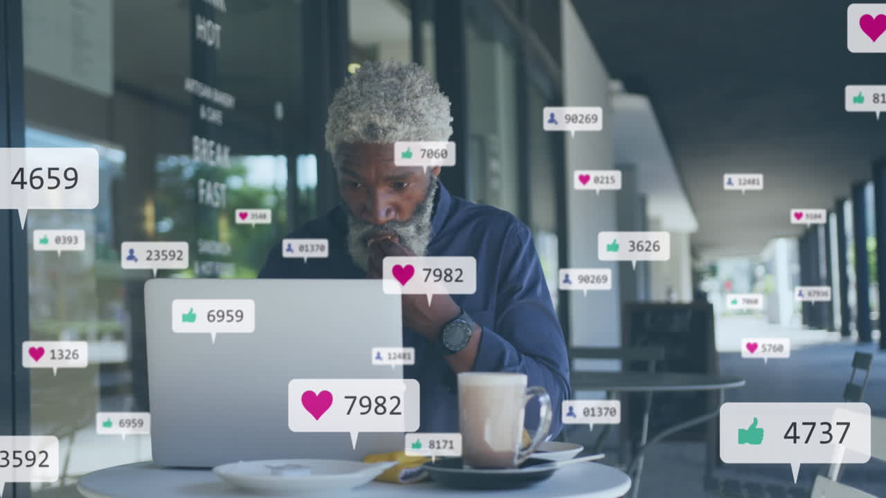 Animation of social media icons and numbers over african american man using laptop