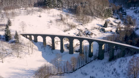 stone train viaduct above a small village in winter,snow countryside